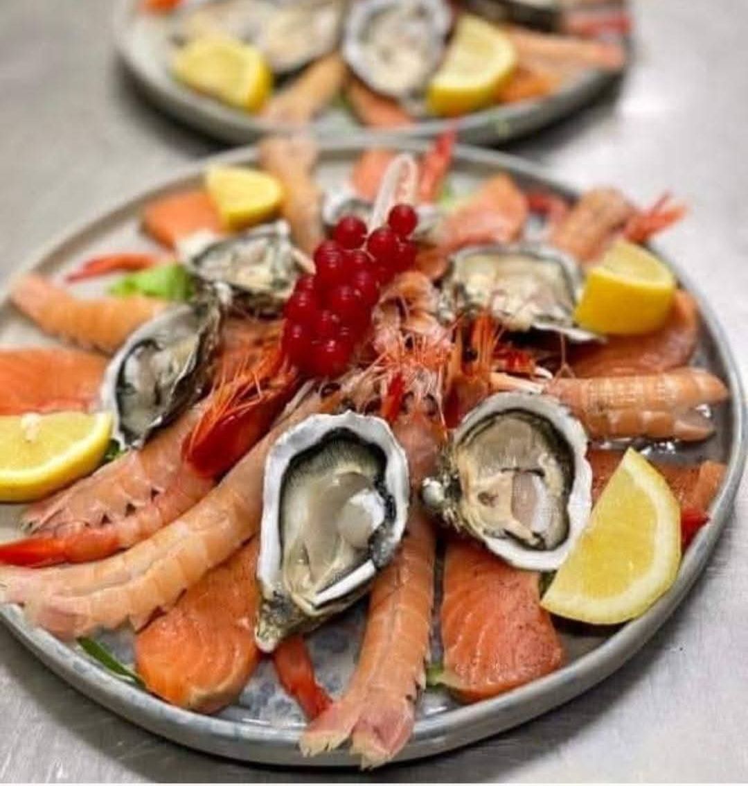 Crudo di mare del catering: ostriche, gamberi rossi, scampi e salmone con limone