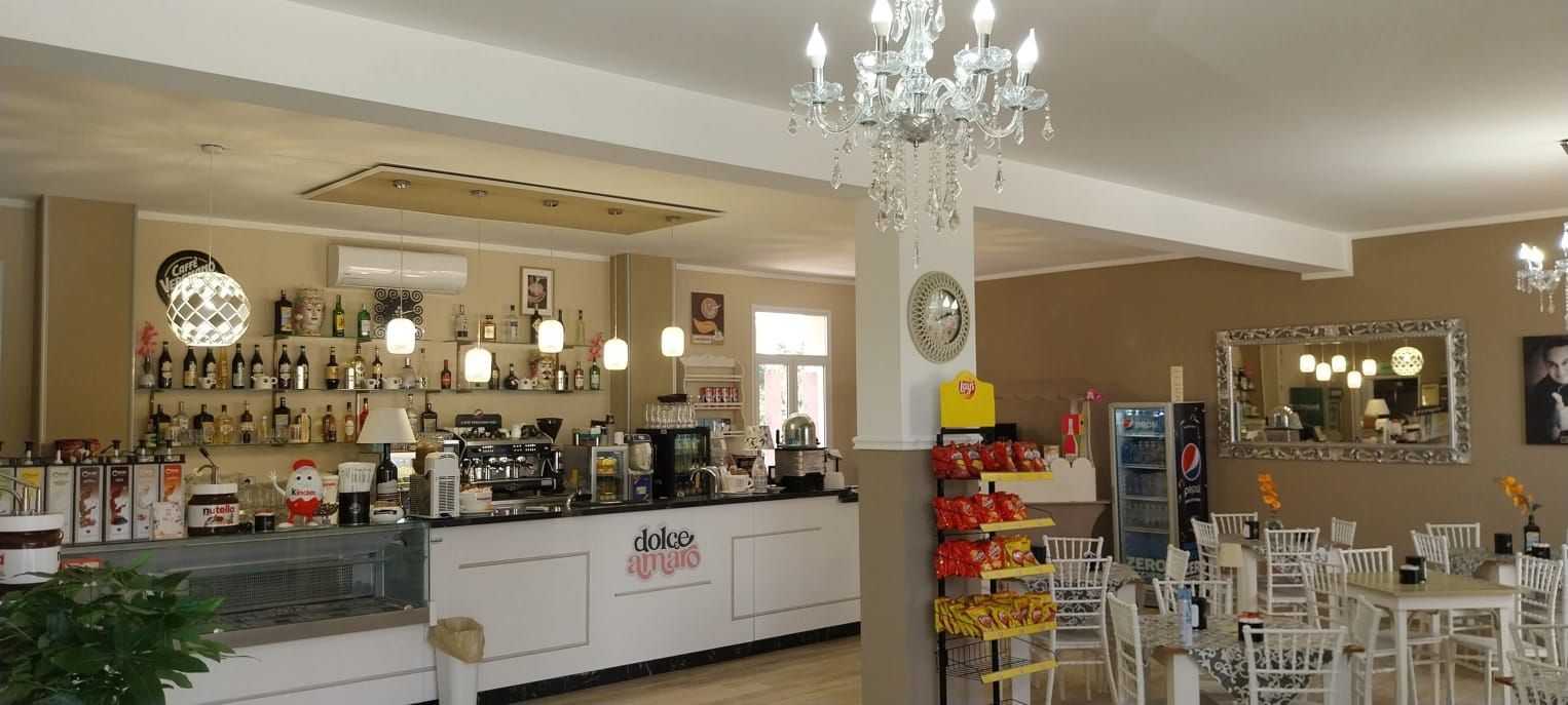 La sala della Caffetteria Dolce Amaro con il bancone bianco e il lampadario di cristallo